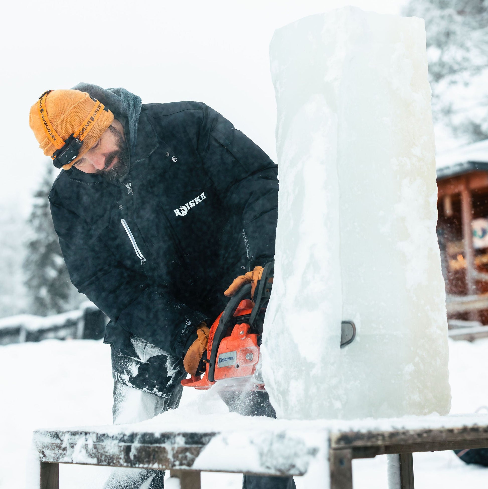 Person using a chainsaw to cut ice in a snowy setting