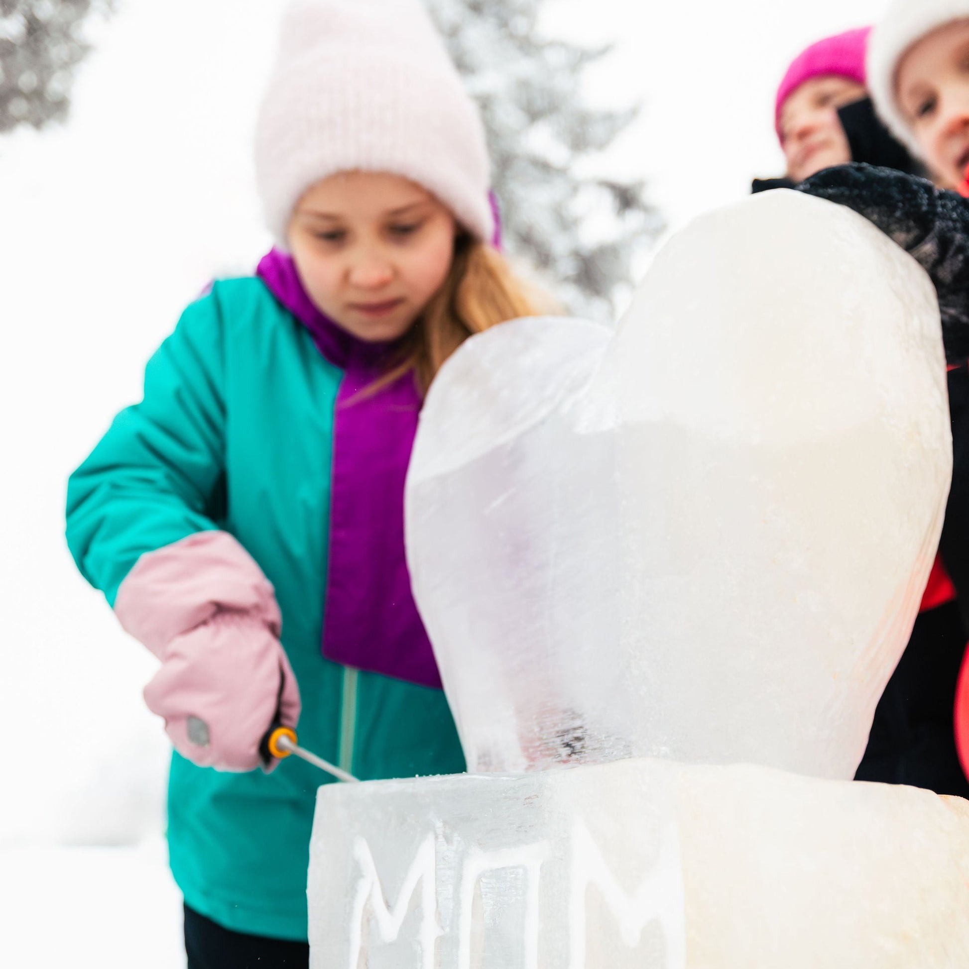 Children playing with a snow sculpture outdoors in winter.