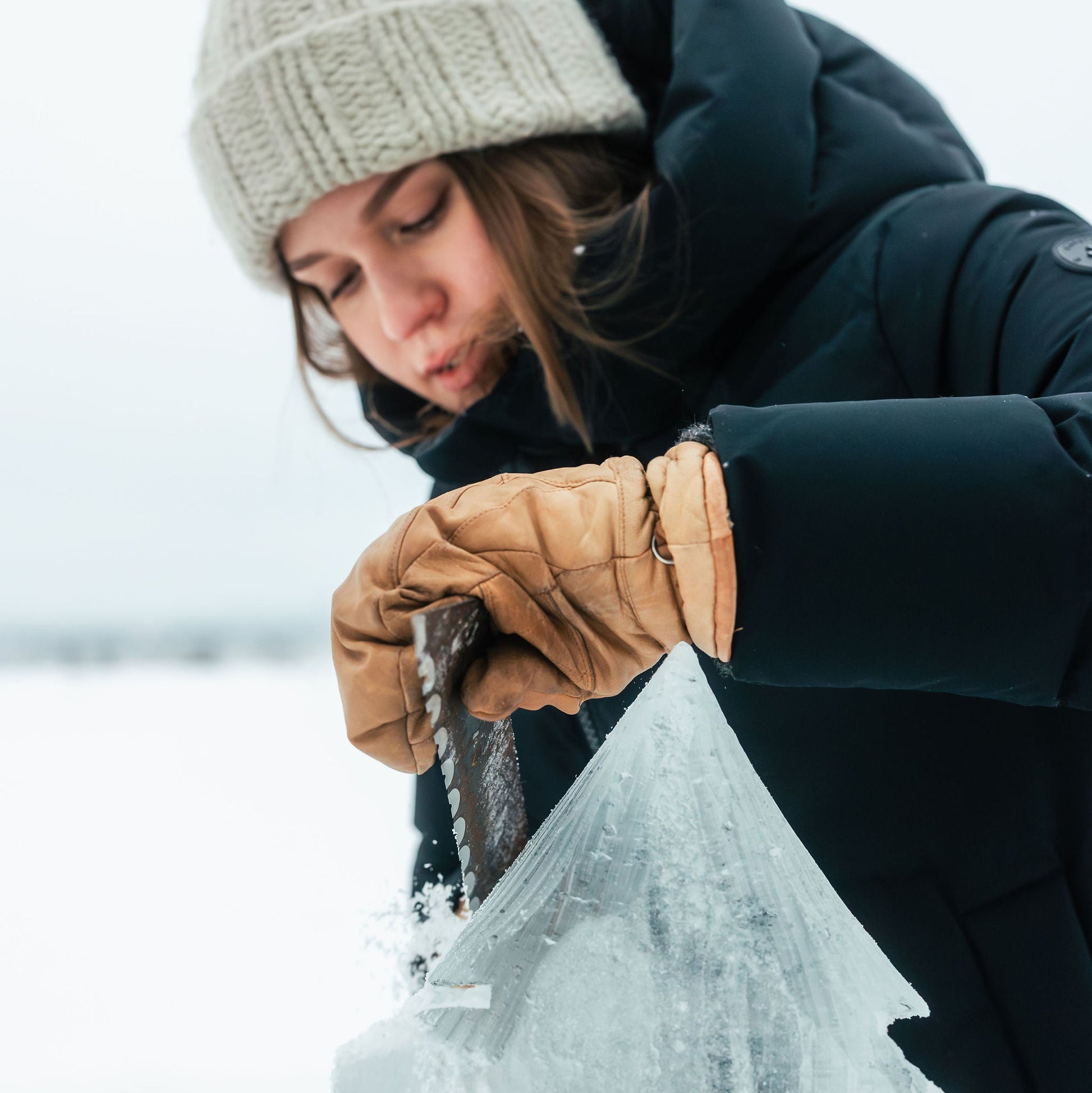 Person in winter clothing holding a block of ice against a snowy background
