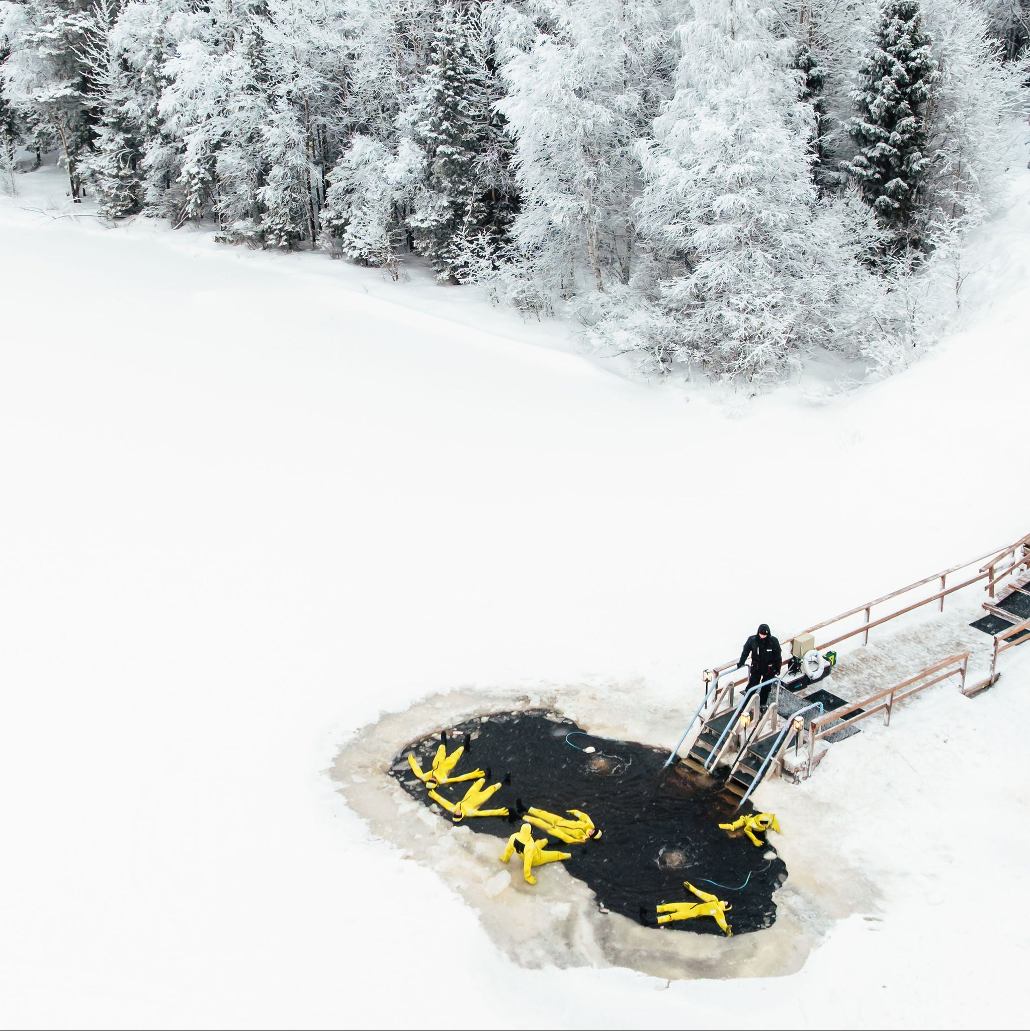 Person on a snowmobile on a frozen lake with snow-covered trees in the background