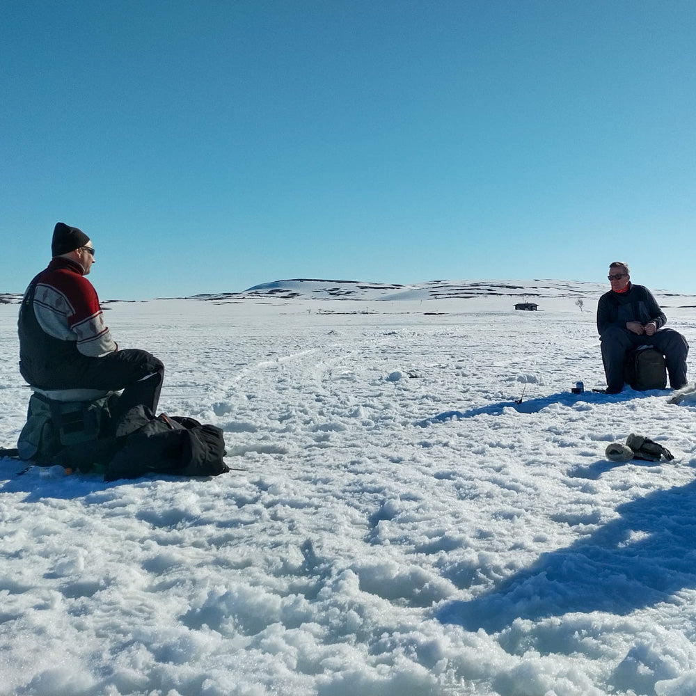 Two men doing ice fishing during a sunny day