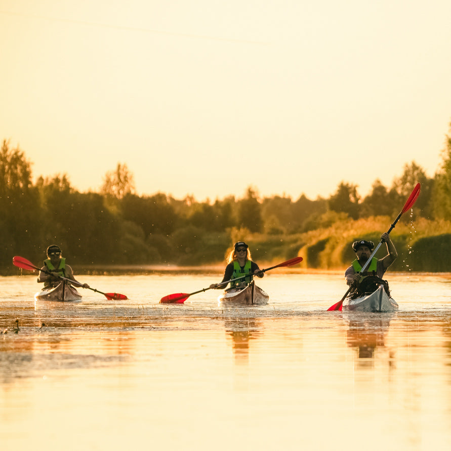 Three friends kayaking under the midnight sun in Rovaniemi