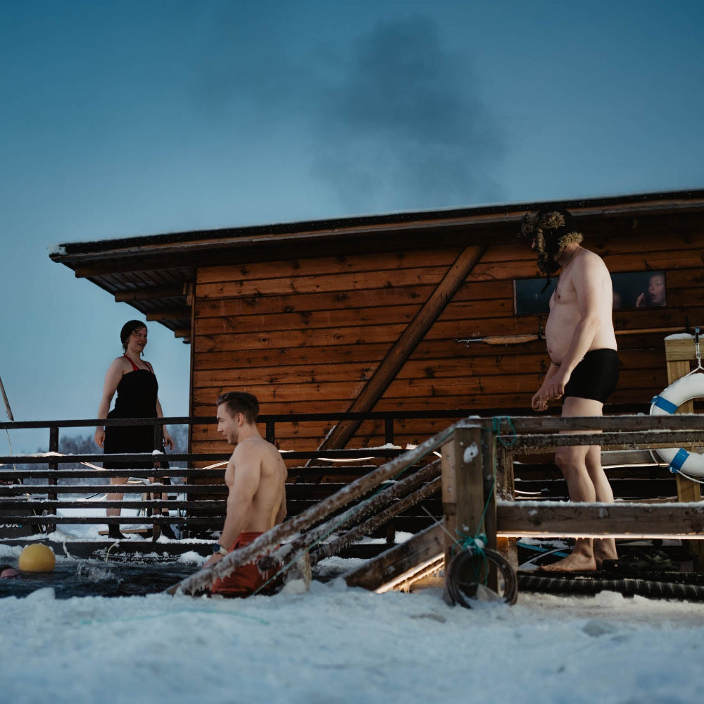 Two men are walking down the stairs for a cold water plunge at Roiske Arctic Sauna Retreat's ice swimming area