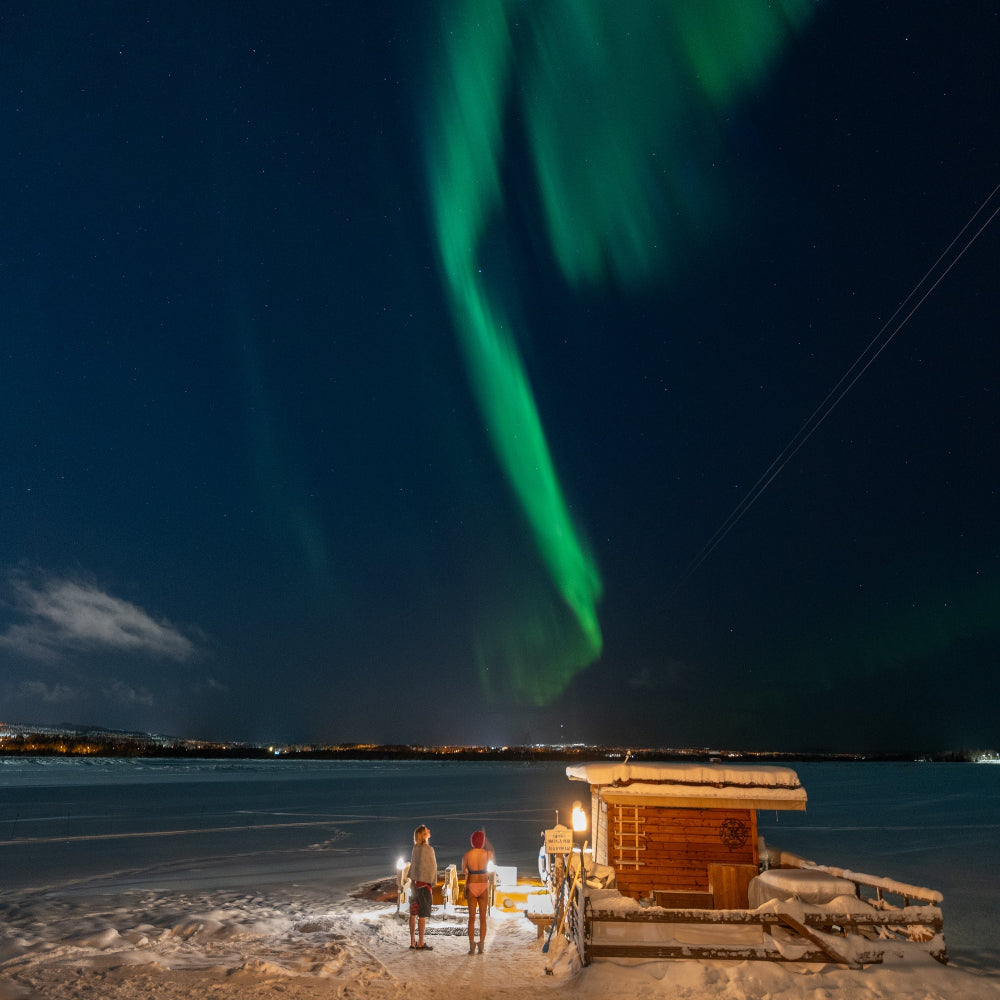 People watching northern lights at Roiske Arctic Sauna Retreat after sauna and ice swimming 