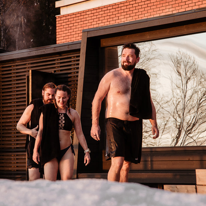 Three people coming from sauna and heading for an ice swim at Roiske Arctic Sauna Retreat