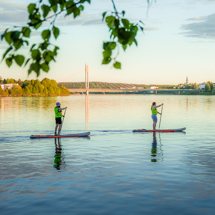 Two friends paddleboarding near the Lumberjack Bridge in Rovaniemi