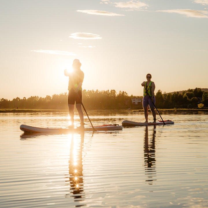 Two friends on SUP-boards under the midnight sun at Roiske Rovaniemi