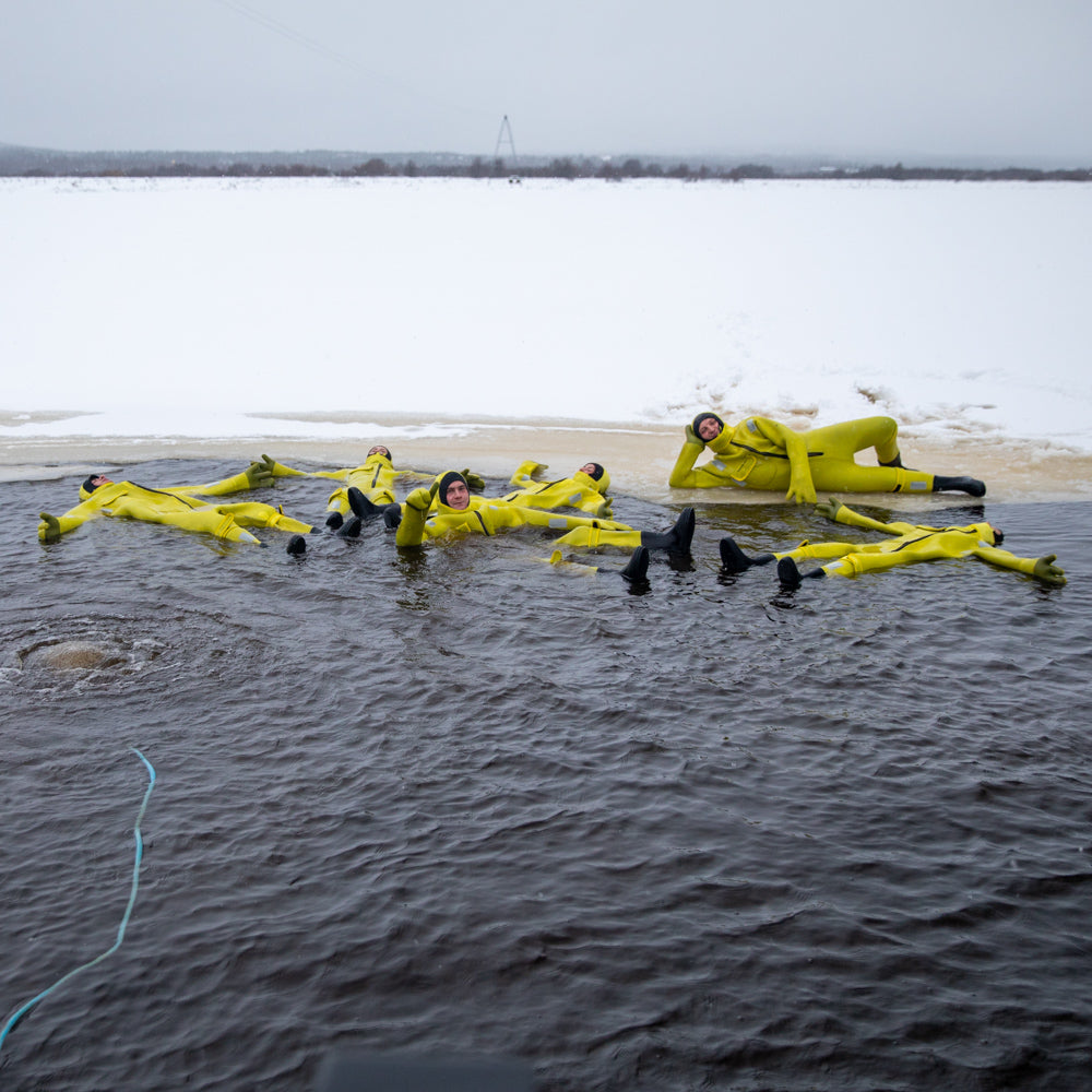 People floating in frozen river with immerion suits at Roiske Arctic Sauna Experience