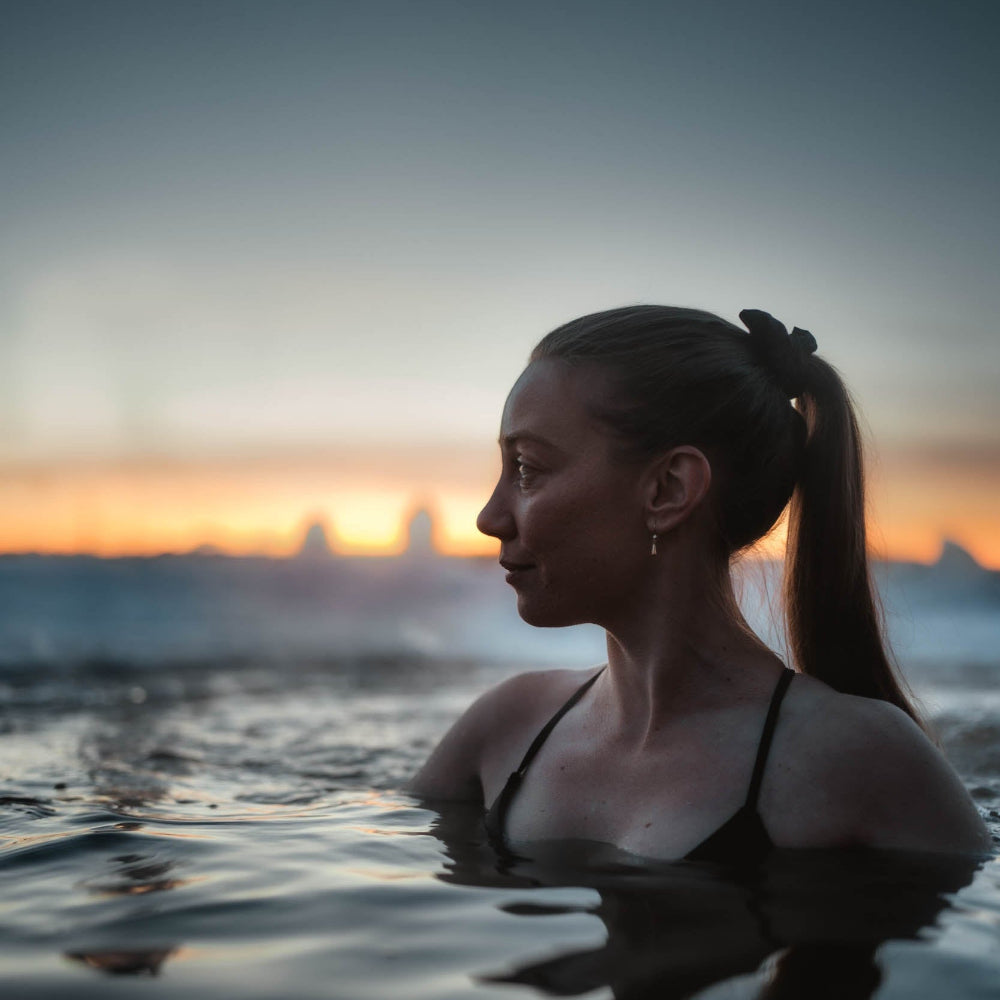 A woman calming down in cold water at Roiske Arctic Sauna Retreat