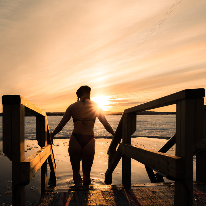 An ice swimmer is going to have a cold water plunge during sunset