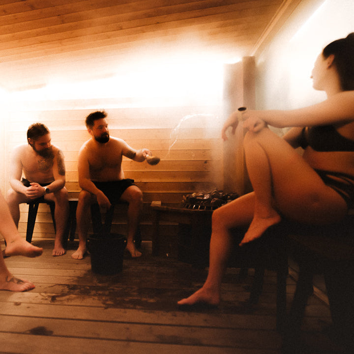 People are sitting in sauna and throwing water to a hot stove to get some löyly