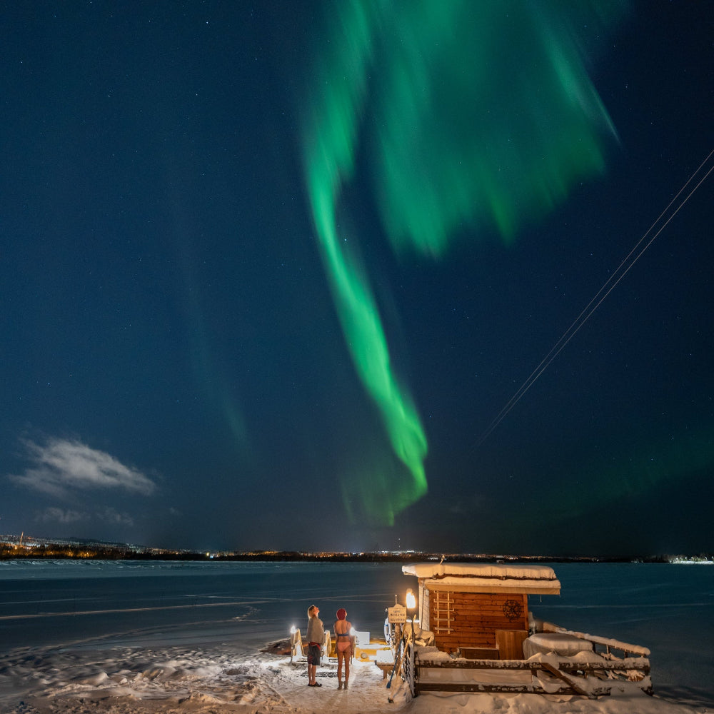 People watching northern lights after ice swimming at Roiske Arctic Sauna Retreat