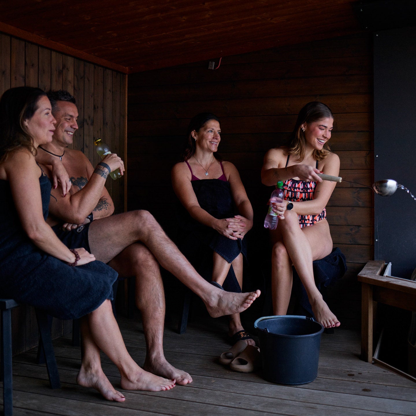 Four people sitting in sauna and enjoying the löyly